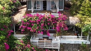 A two-story building with a thatched roof and pink bougainvillea vines. - Villa Deeksha tropicale ocean view Bingin (Bingin Kuta Selatan)
