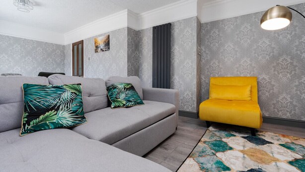A modern living room with a grey sectional sofa, a yellow armchair, and a patterned rug. - Boutique 3bd Opposite Etihad & Coop - Free Parking (Greater Manchester)