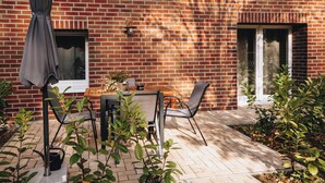 Een bakstenen huis met een terras, een tafel, stoelen en een raam.