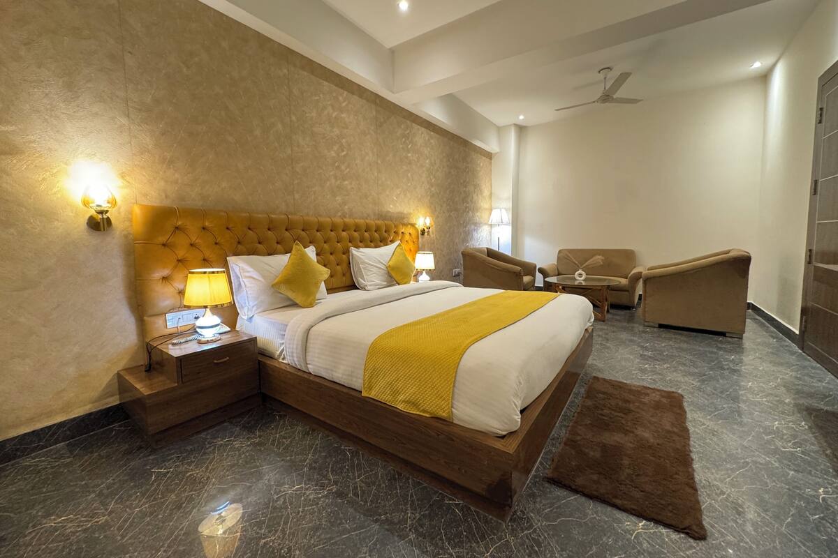 A modern hotel room with a large bed, two bedside tables, a sofa, and a ceiling fan.