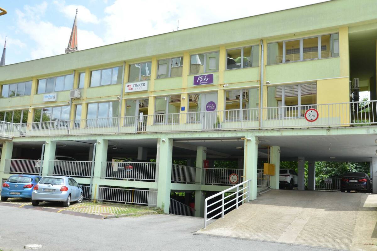 A multi-story building with a ground-level parking area.