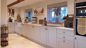Een moderne keuken met witte kastjes, een inbouwoven en een raam met uitzicht op de lucht.