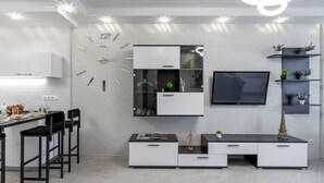 A modern kitchen with a built-in clock, a dining area with bar stools, and a TV mounted on the wall. - Modern apartments  near Dana Mall (Minsk)
