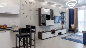 A modern kitchen with a built-in clock, bar stools, and a dining area with a blue rug. - Modern apartments  near Dana Mall (Minsk)