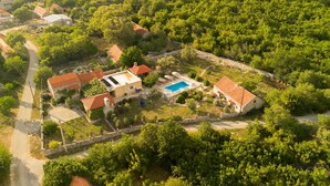 An aerial view of a residential area with houses, a swimming pool, and surrounding greenery.