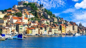 A coastal town with historic buildings, a prominent castle, and a marina with boats.