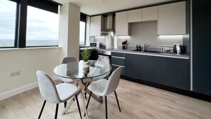 Une cuisine moderne avec une table et des chaises en verre, un four à micro-ondes et une vue sur la ville.
