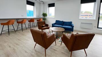 Un espacio de oficina moderno con un sofá azul, sillas marrones y una mesa redonda.