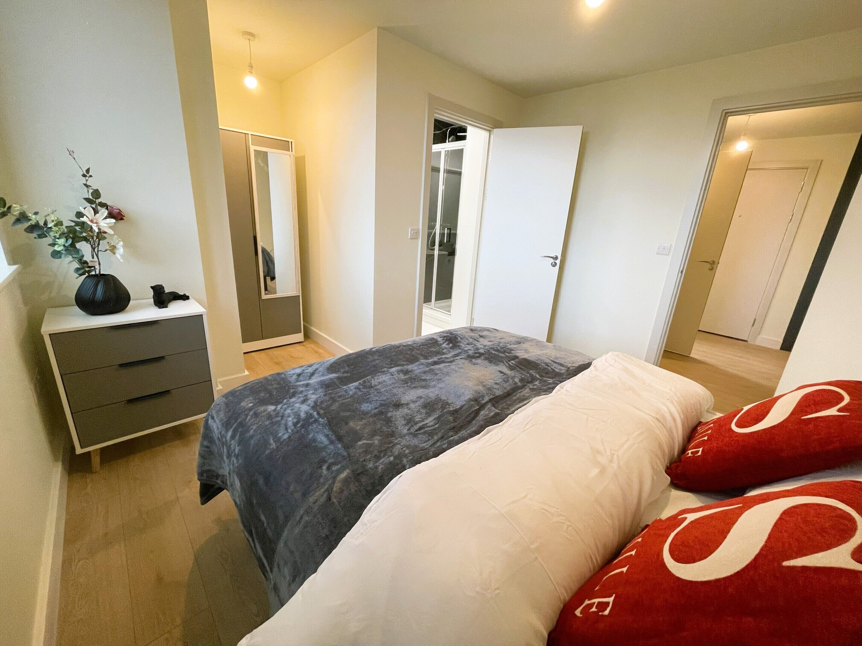 Quarto com cama, mesas de cabeceira, espelho e guarda-roupa.