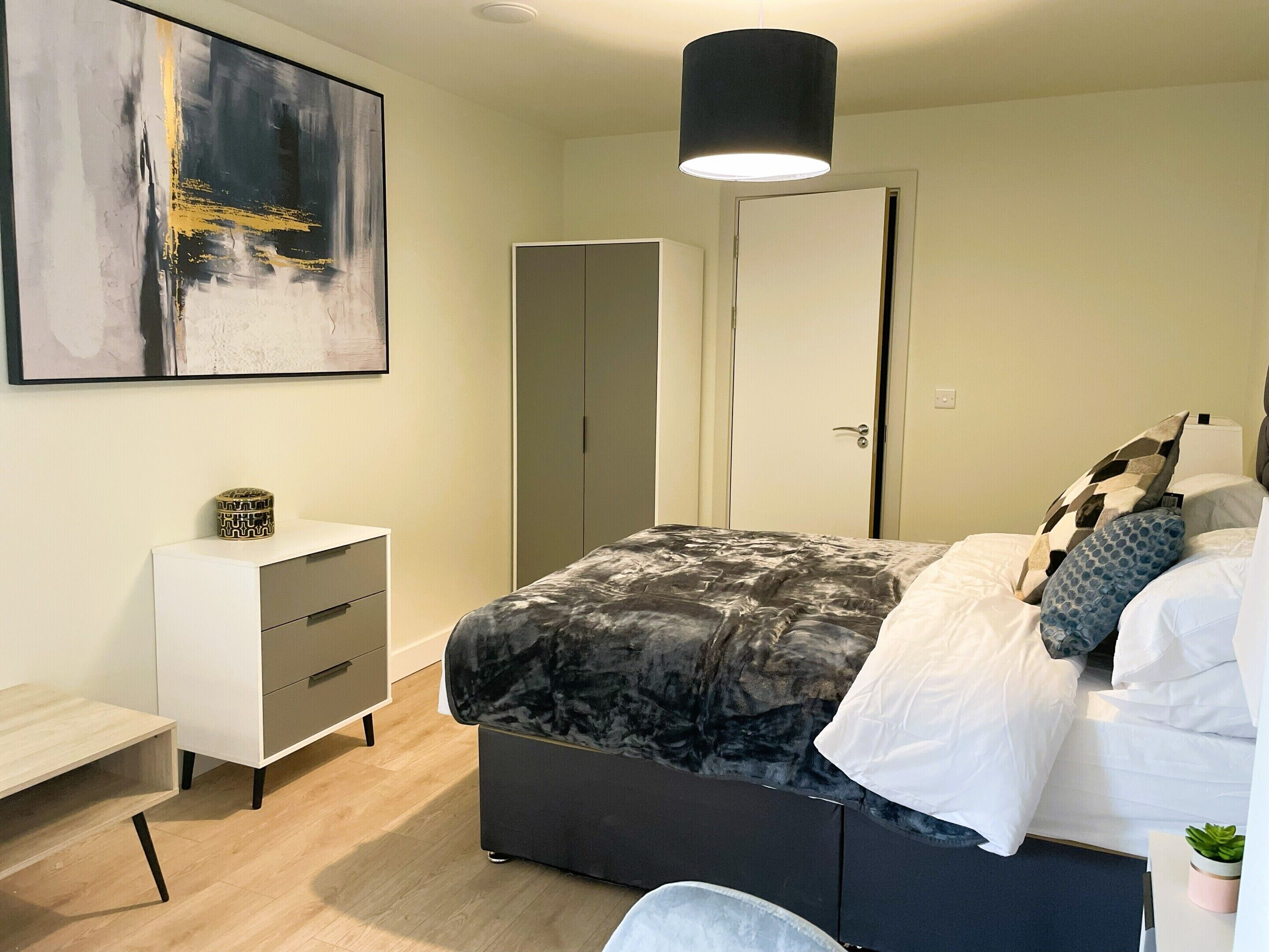 Quarto moderno com cama, mesa de cabeceira, guarda-roupa e um quadro na parede.