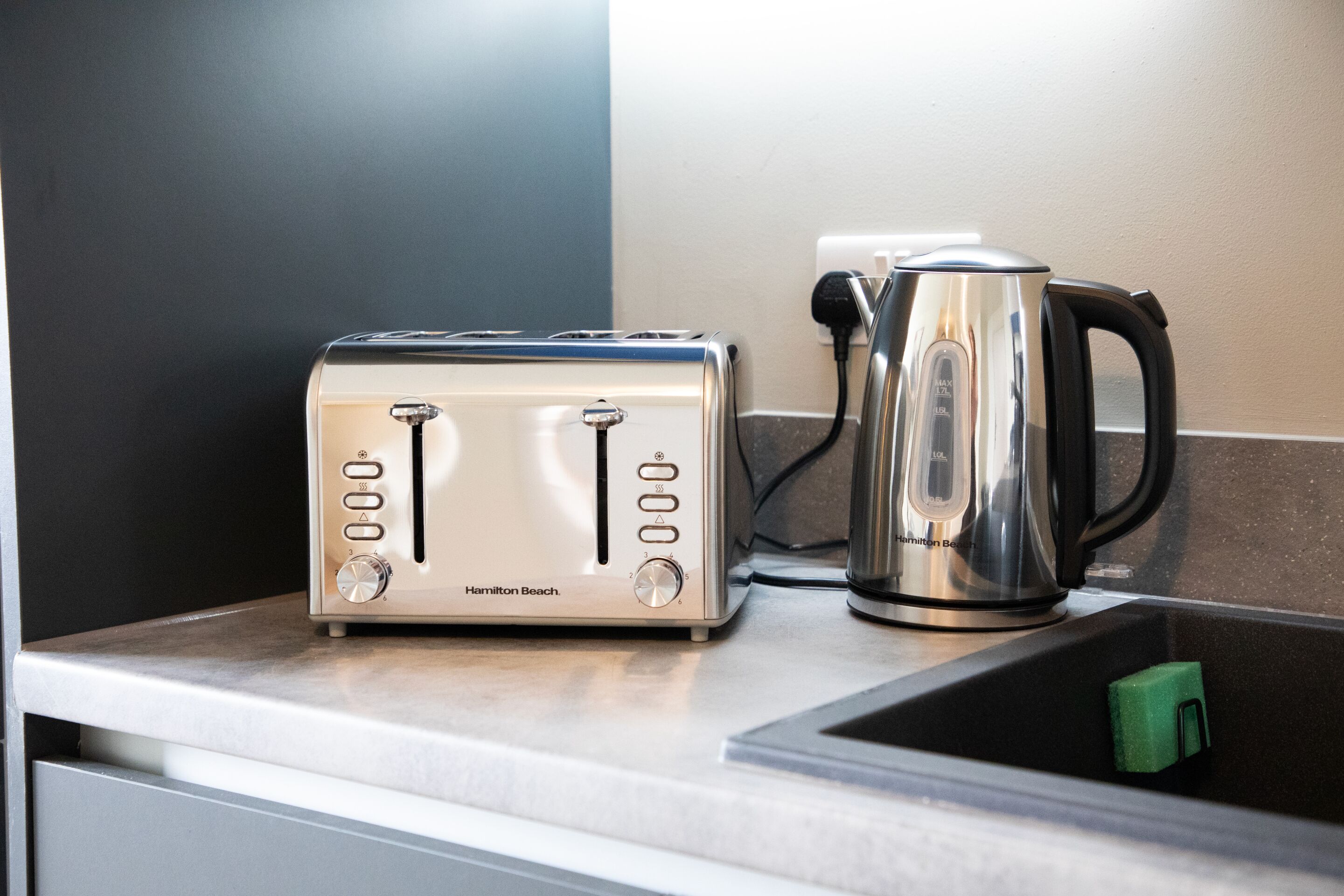 A kitchen counter with a Hamilton Beach toaster and a stainless steel kettle.