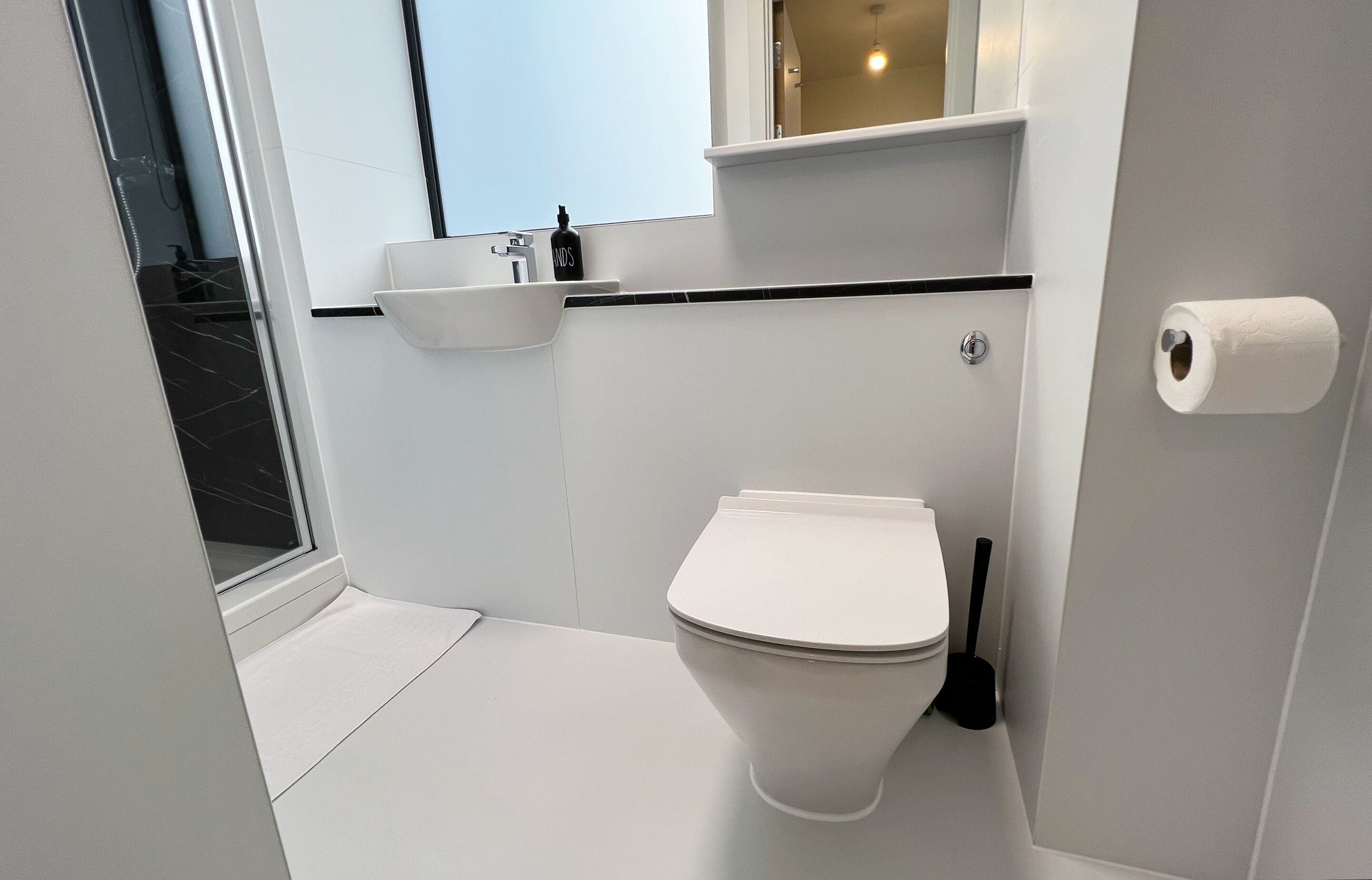 Een compacte, moderne badkamer met toilet, wastafel en een raam.