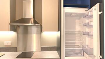 A modern kitchen with a stainless steel range hood, a built-in oven, and a refrigerator with clear storage bins.