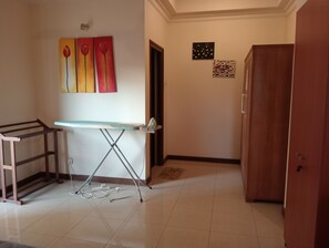 Cozy retreat with ironing station, wooden wardrobe, and artwork adorning the walls.