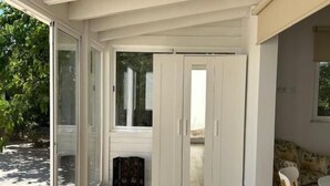 A spacious room with a wooden floor, a sliding glass door leading to a patio, and a small table with a chair. - Quinta Verde Algarve (Faro)