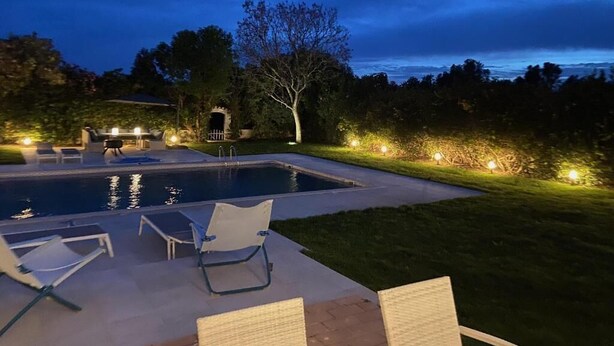 A swimming pool with lounge chairs and a barbecue area, surrounded by a well-lit garden at dusk. - Quinta Verde Algarve (Faro)