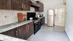 Eine Küche mit dunklen Holzausziehtüren, einer gefliesten Spritzschutzwand, einem Herd, einem Kühlschrank und einer Tür.