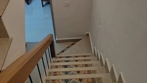Eine Treppe mit gemusterten Fliesen führt zu einem Raum, der ein Bett und einen Nachttisch beinhaltet.