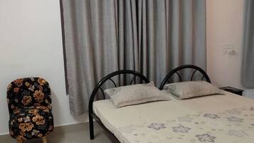A bedroom with a bed, two pillows, a chair, and a curtain.