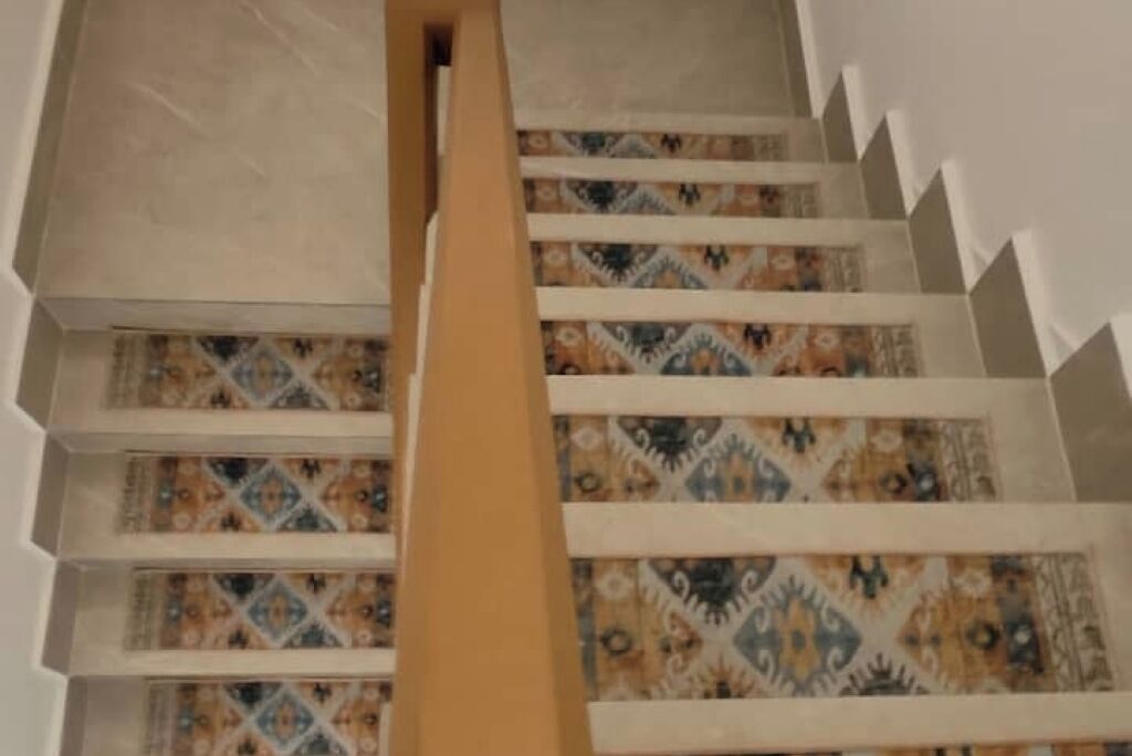 Una escalera con baldosas estampadas y barandillas blancas.