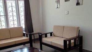 A living room with two sofas and a small round table. - Genesis Spaces 12 guests, 6 bedrooms, 4 AC+ 2 non AC bedrooms (Kottayam)