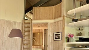 A modern living room with a sofa, a coffee table, a TV, and a wooden bookshelf. - FeWoHuett - cozy vacation home in the Hüttener mountains near the Baltic Sea (Brekendorf)