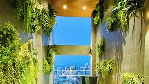 A narrow corridor with green walls, a city view, and colorful seating areas.