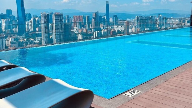 A swimming pool with a cityscape view, including modern skyscrapers.