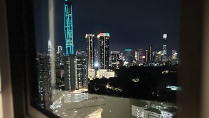 A nighttime cityscape viewed through a window, featuring illuminated skyscrapers and a highway.