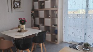 A dining area with a table, chairs, a bookshelf, and a window with a view. - Seafront apartment. All on foot (Saint-Cyprien)