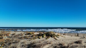 A beach with a wooden fence and vegetation in the foreground, leading to the ocean. - Seafront apartment. All on foot (Saint-Cyprien)