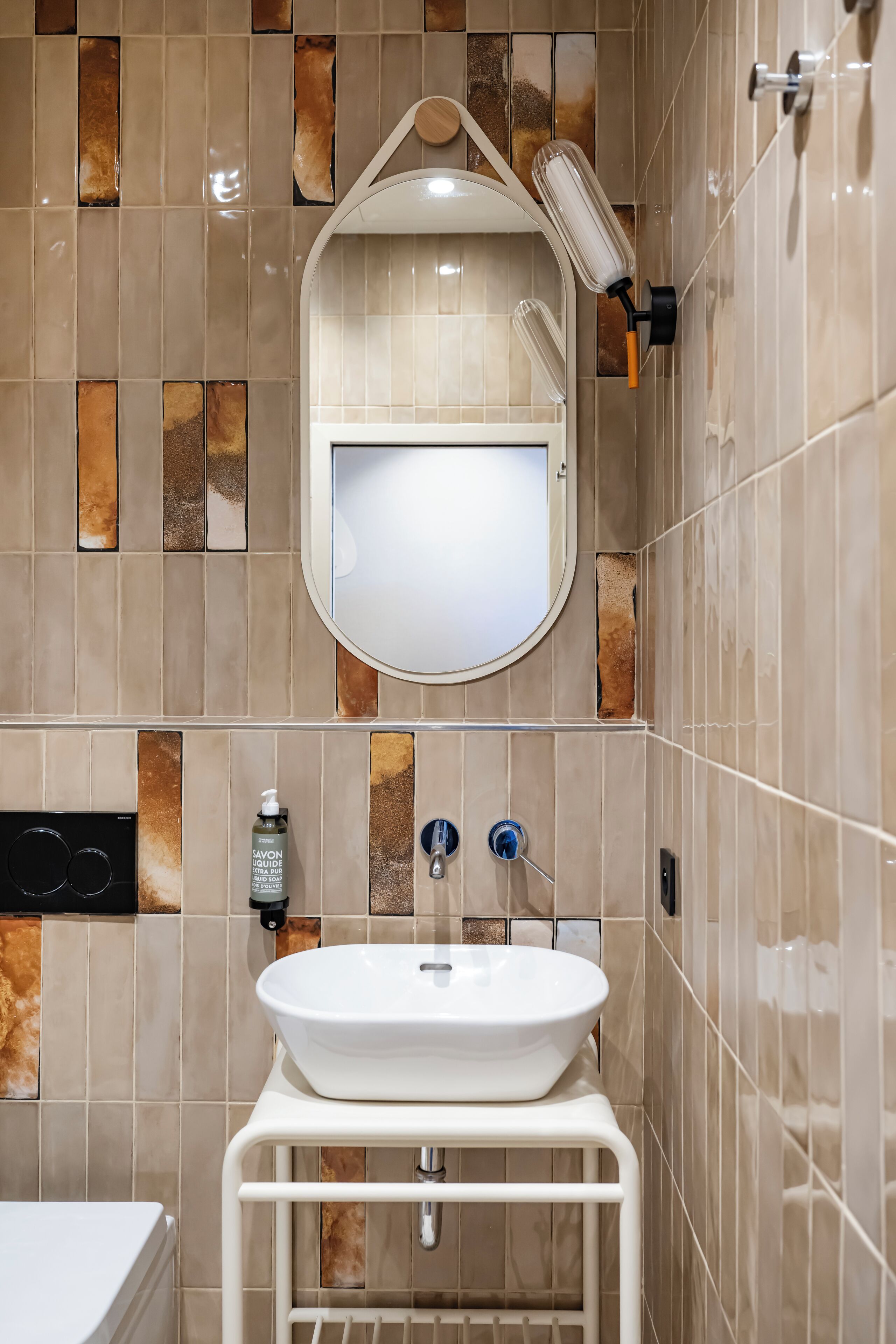Un baño con lavamanos blanco, un espejo y un cabezal de ducha manual.