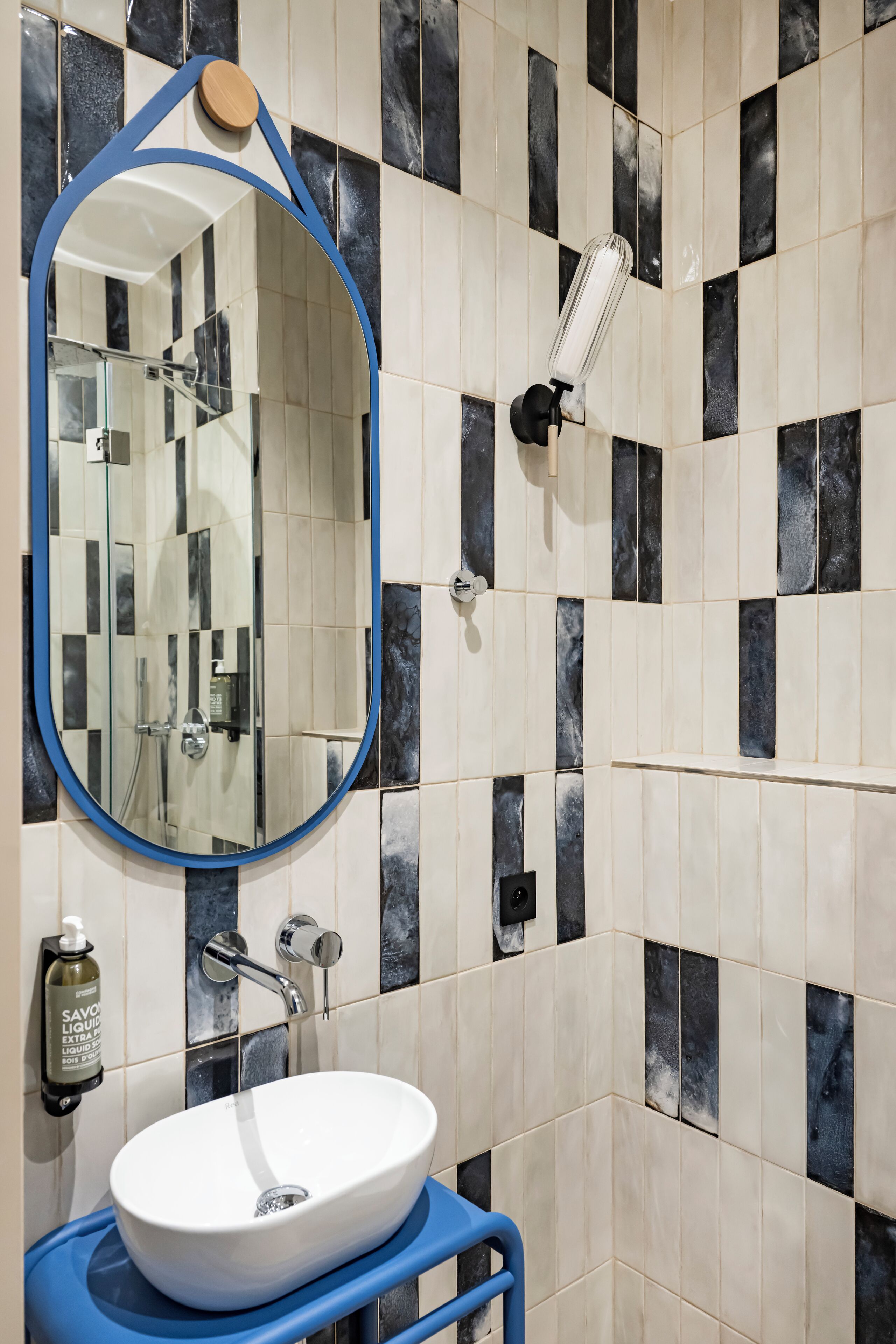 Ein Badezimmer mit einem weißen Waschbecken, einem blauen Handtuchhalter und einem Spiegel mit Holzrahmen.