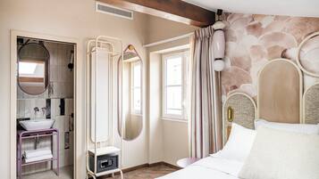 A bedroom with a bed, a vanity with a mirror, a window, and a stone-patterned wall.