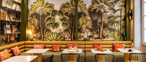 A restaurant with a tropical mural, green and yellow seating, and white tables.