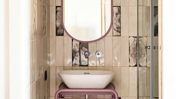 A bathroom with a white sink, a mirror, and a glass shower enclosure.