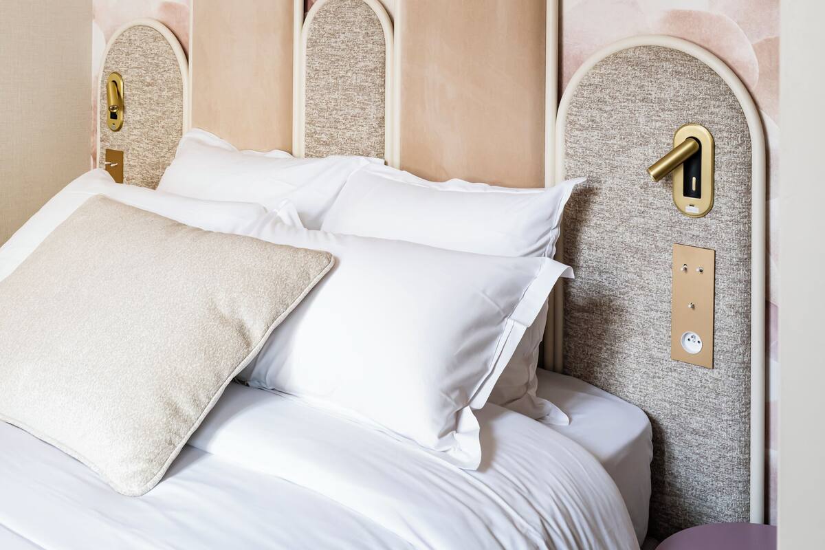 Un lit avec une tête de lit, un mur orné d’un motif texturé et une table de chevet.
