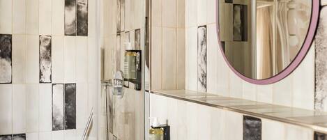 A modern bathroom with a freestanding sink, a glass shower enclosure, and a mirror with a purple frame.