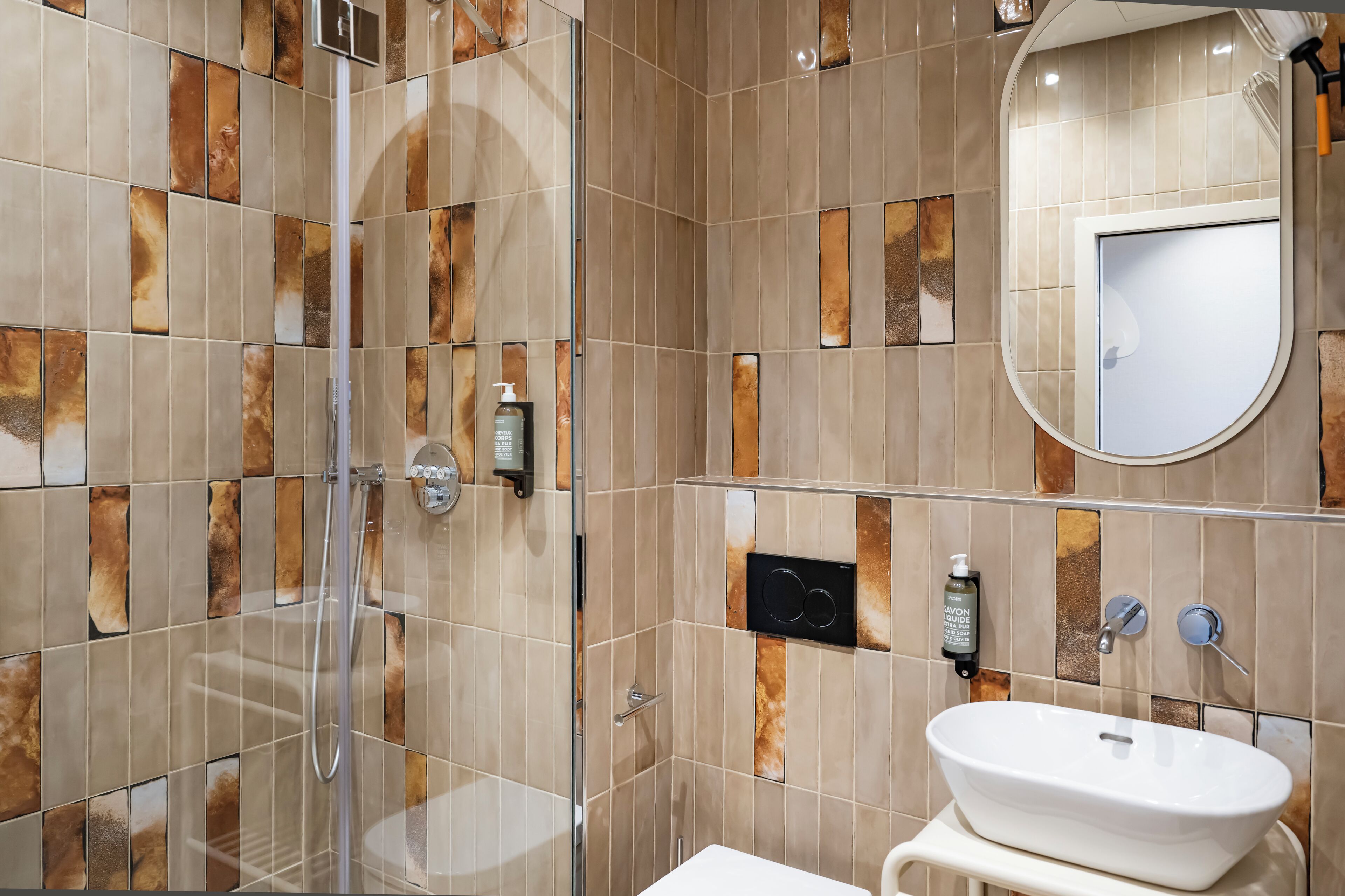 A bathroom with a glass-enclosed shower, a white sink, and a mirror.