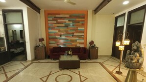 Uma sala de estar ampla, com sofá, mesa de centro, decoração na parede e uma estátua.
