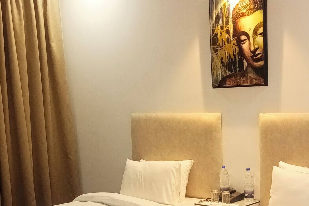 A hotel room with two beds, a Buddha painting, a ceiling fan, and a wooden floor.