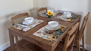 A wooden dining table with white bowls and glasses, surrounded by chairs. A vase with sunflowers is on the table. - Close Central London 1 bed Apartment Sleeps 3 (London)