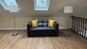 A room with a dark sofa, two lamps, and a window with a view of trees. - Close Central London 1 bed Apartment Sleeps 3 (London)