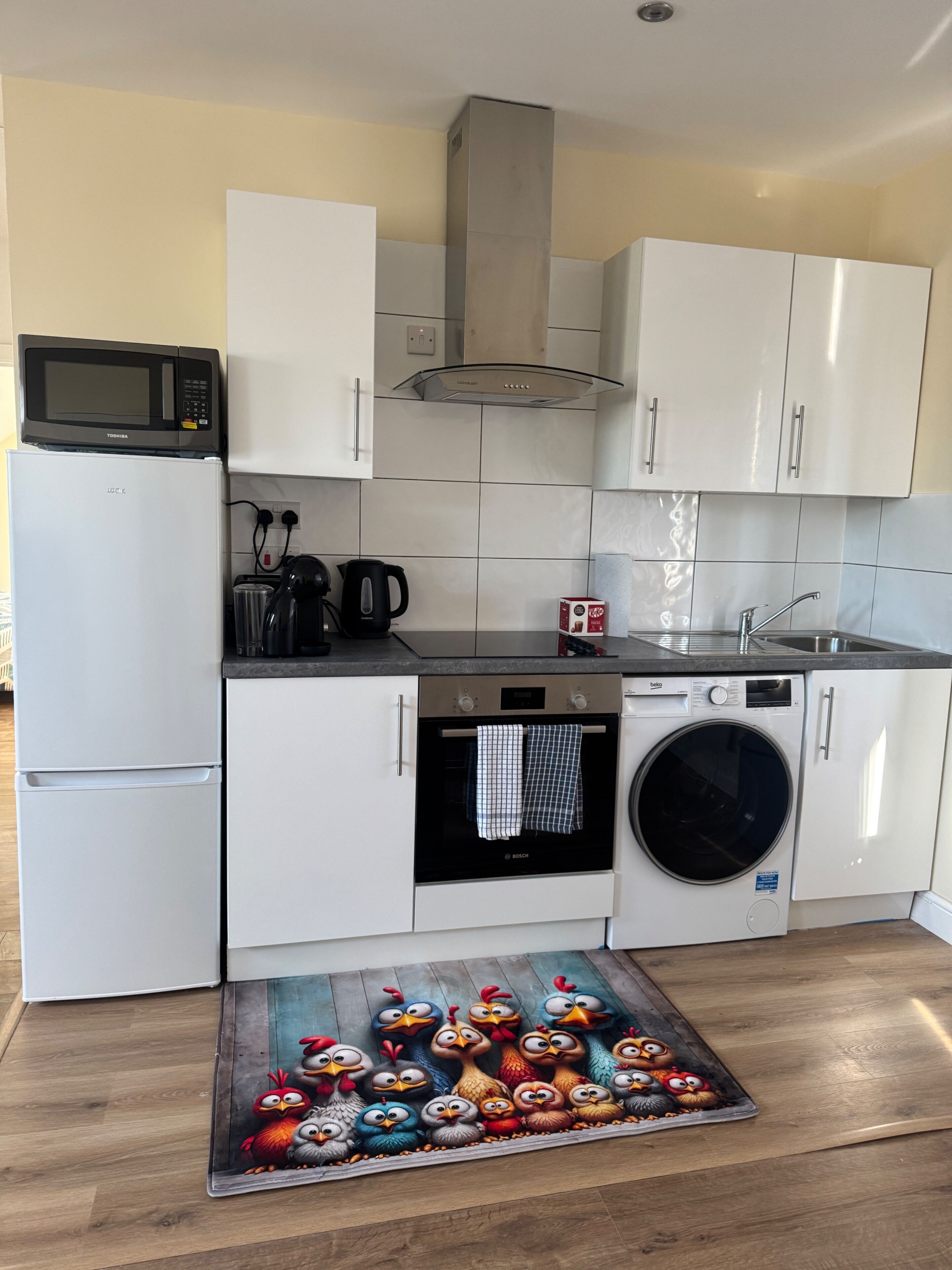 A modern kitchen with white cabinetry, a microwave, a Bosch oven, and a Bosch washing machine.