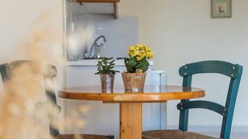 Una mesa de comedor con dos sillas, una cocina al fondo y un cuadro en la pared.