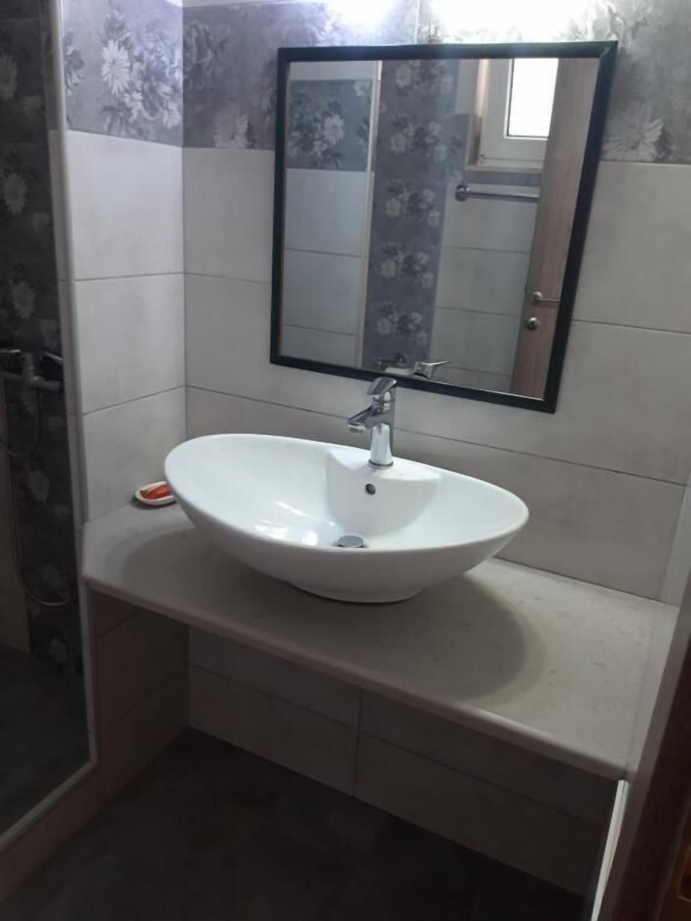 A bathroom with a white sink, a mirror, and tiled walls.