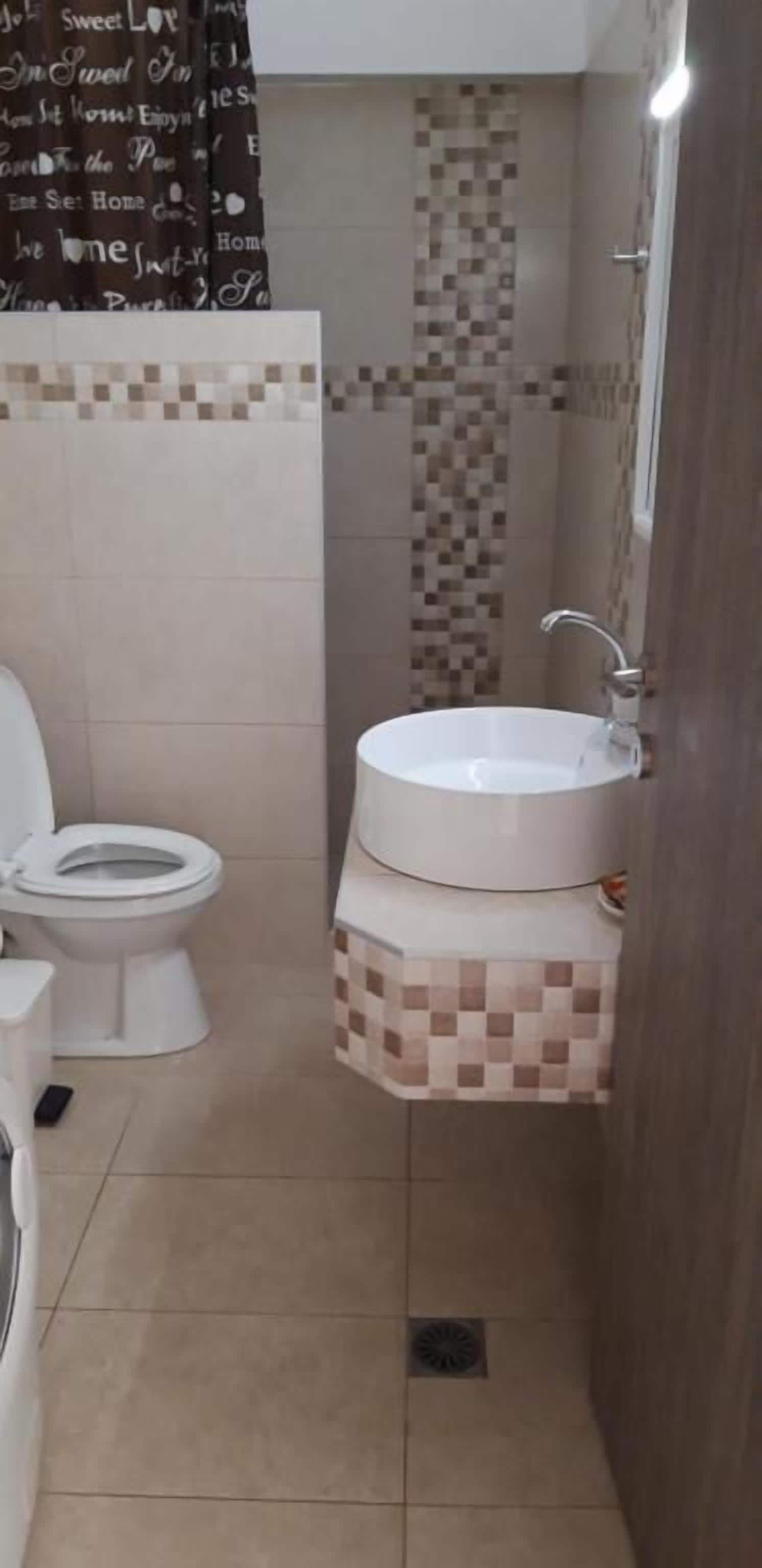A small bathroom with a toilet, a sink, and a shower area.