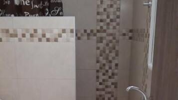 A small bathroom with a toilet, a sink, and a shower area.
