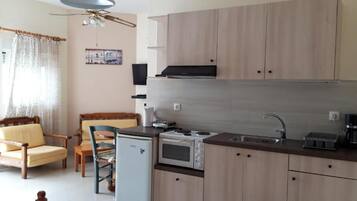 A compact kitchen with wooden cabinets, a microwave, a stove, and a sink.