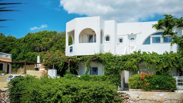 A white building with arched windows and a covered patio area. - Crete Essence Villas-Makrygialos (Ierapetra)